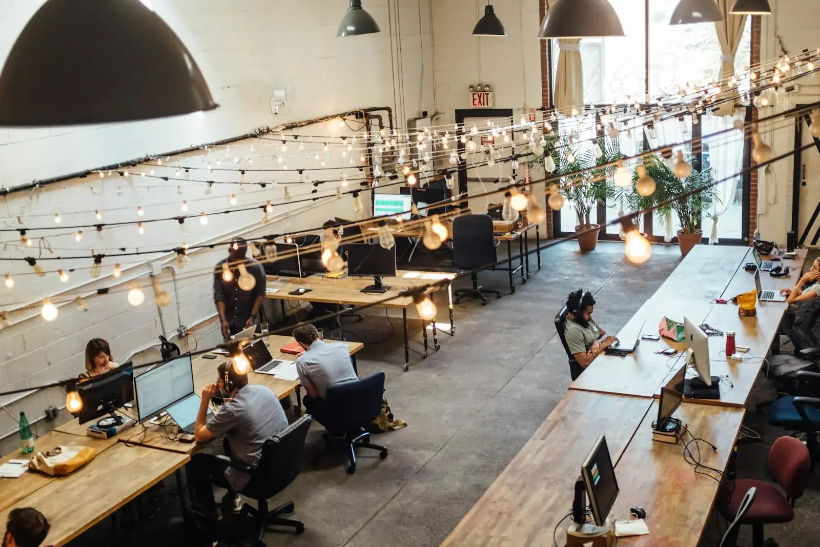 A professional woman in an elegant white outfit stands confidently at a modern office workstation, representing empowered leadership and success in commercial real estate.
