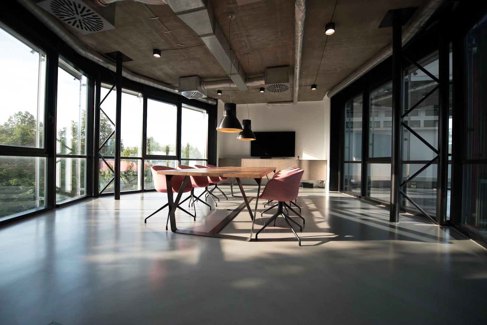 Warm modern office with timber conference table and tall windows